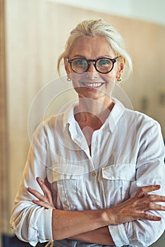 Vertical shot of a young happy mature business woman in white shirt looking at camera and smiling while posing in the