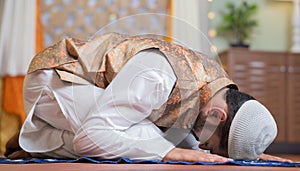 Vertical shot of young indian muslim man doing holy namaz or Salah at home during ramdan festival - concept tredition