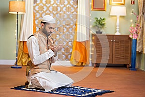 vertical shot of young indian muslim man doing holy namaz or Salah at home during ramdan festival - concept tredition photo