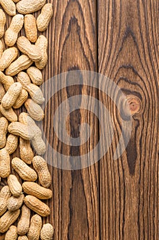 Vertical side border of whole peanuts on wood