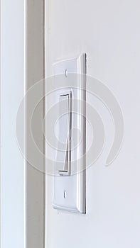 Vertical Side view of electrical rocker light switch mounted on white interior wall