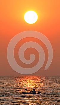 Vertical silhouette of a solo kayaker during sunset on Lake Huron, United States