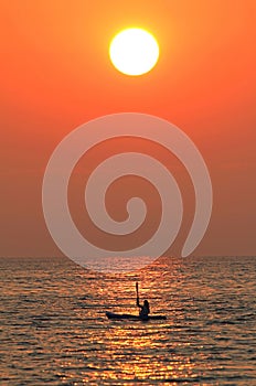 Vertical silhouette of a solo kayaker during sunset on Lake Huron, United States