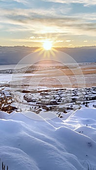 Vertical Snowed in hill overlooking frosted houses and lake in Draper Utah in winter