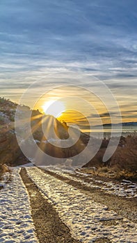 Vertical Snowy dirt road in Provo Canyon overlooking lake mountain and sun at sunset