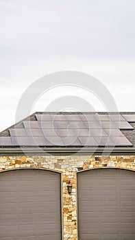Vertical Solar panels installed on the garage roof of a home with cloudy sky background