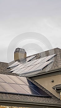 Vertical Solar panels mounted on the dark pitched roof of a home under cloudy gray sky