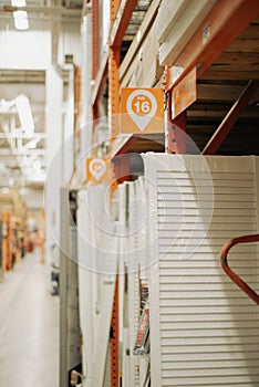 Vertical stacks of doors and panels with Bay number and blurred view of the high industrial ceiling. The image captures scale,