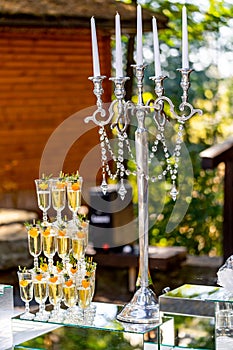 Vertical stand of champagne in the glasses. Candelstick with pearl thread. Nice tender decoration