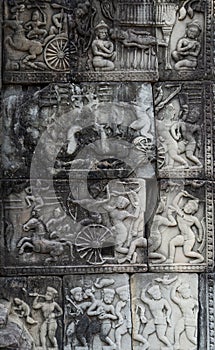 Vertical of stone carvings of Khmer warriors in chariots and war horses in Angkor Wat temple