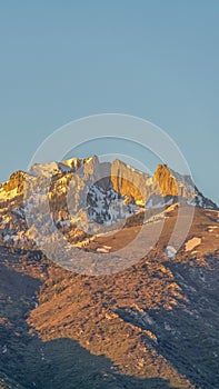 Vertical Striking mountain peak with rugged slopes against blue sky on a sunny day