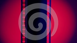 Vertical strip of blank film on a blue background with a red circular light close up. Processing negatives. Copy space.