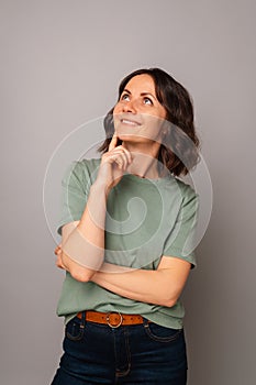 Vertical studio portrait of a middle aged woman holding hand to chin thinking.