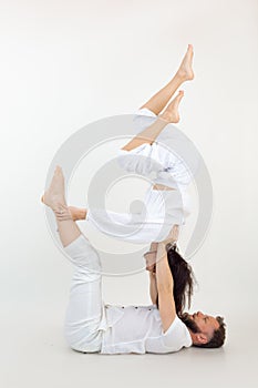 Vertical studio shot of man and woman, family doing sports exercises, fitness and yoga. Acroyoga instructor in studio