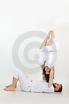 Vertical studio shot of man and woman, family doing sports exercises, fitness and yoga. Male holding female upside down