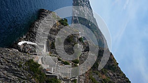 Vertical stunning view over Amalfi coast in Italy with picturesque Praiano village, steep stone staircase on steep cliff