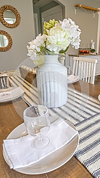 Vertical Table setting inside a dining room with brown table and white chairs photo