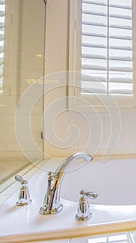 Vertical tall frame Bathroom interior with built in bathtub and shiny towel rod on the white wall