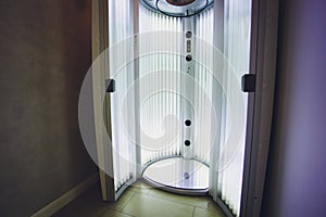 Vertical Tanning turbo Solarium Light Machine with glowing blue light ultraviolet lamps for tanning and skin care. Empty