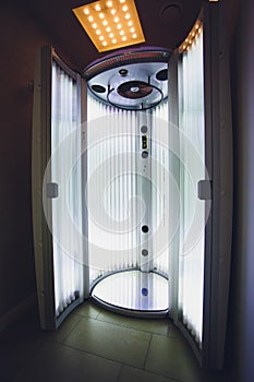 Vertical Tanning turbo Solarium Light Machine with glowing blue light ultraviolet lamps for tanning and skin care. Empty