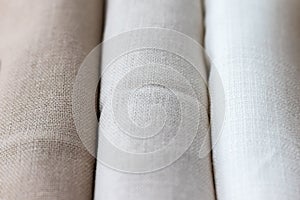 Vertical textural background of three types of natural linen fabric, rolled up