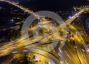 Vertical top down aerial view of traffic on freeway interchange at night.