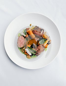 Vertical top shot of a gourmet dish with meat, vegetables, and sauce