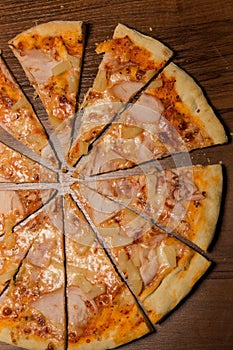 vertical top view closeup sliced pizza with prosciutto and pineapple