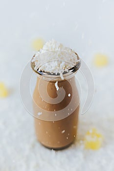 Vertical top view of a glass of chocolate milkshake on a table, with cream on top