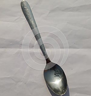 Vertical top view shot of table kitchen silver spon isolated. Silver spon is on a white linens background with negative space. photo