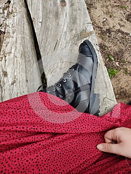 Vertical top view of a woman wearing black boots and a red skirt, sitting on a bench at the beach