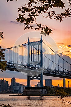 Vertical of the Triborough Bridge at sunset with an orange cloudy sky in the background, New York