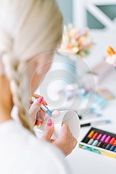 Vertical unrecognizable photo of woman artist hands jobbing, making decoration crafts flowers on mugs of polymer clay.