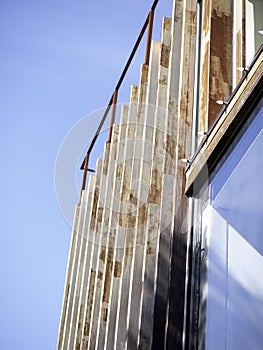 Vertical: Urban, modern building with vertical slats, window and blue sky.