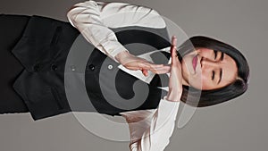 Vertical Video Asian receptionist expressing timeout symbol on camera