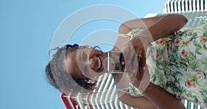 Vertical video. Carefree African American young woman chatting in a city in summer