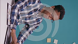 Vertical video: Exhausted worker doing timeout sign with hands in front of laptop