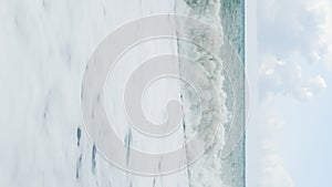 Vertical video. Foamy sea waves on cloudy day. Scenic seascape.