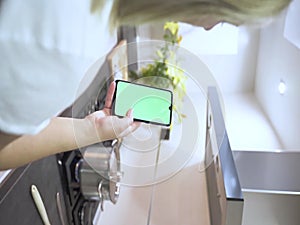 Vertical video girl using the phone green display on the cosciana, hands holding the chrome key business smartphone fingers