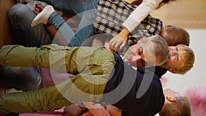 Vertical video of happy children hugging their teacher, a man with gray hair in a purple T-shirt in a club for preparing