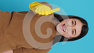 Vertical video: Joyful maid posing in studio doing approve gesture in front of camera after finishing cleaning