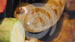 Vertical video. Lubricate grilled sausages with oil with a brush while frying.