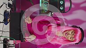 Vertical video: Musician with pink hair performing techno music using dj mixe