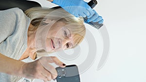 Vertical video, an old woman at an appointment with a trichologist. Hair care and treatment