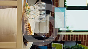 Vertical video Panning shot of empty cozy apartment living room with appetizer platter and wine bottle on table