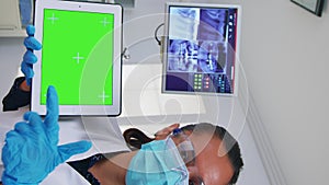 Vertical video: Patient pov of dentist analisyng x-ray using tablet with green screen