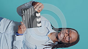 Vertical video: Portrait of african american woman holding film slate board
