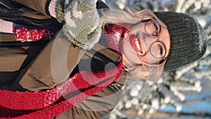 VERTICAL VIDEO POV portrait happy winter woman blowing snowflakes sunny frozen forest closeup slowmo