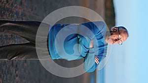 VERTICAL VIDEO POV relaxed mature man standing on beach with crossed hands contemplate sunset nature