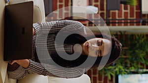 Vertical video Teleworker sitting on couch, focused on finishing tasks in personal office